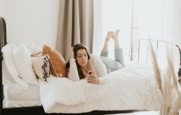 Frau liegt auf Bett mit Handy