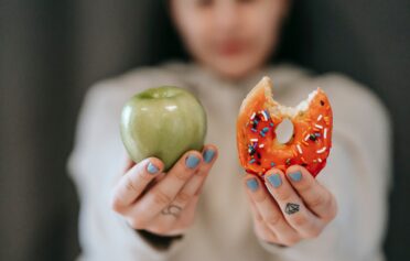 Frau hält Donut und Apfel