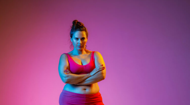 Starke Frau in Sportklamotten mit pinkem Hintergrund