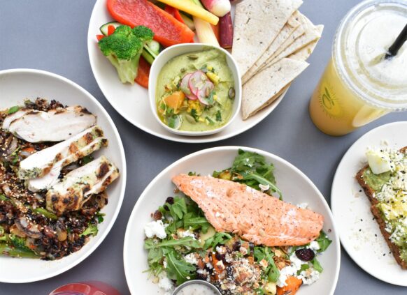 verschiedene Teller mit proteinreichen Gerichten, wie Lachs, Gemüse, Huhn, Brot