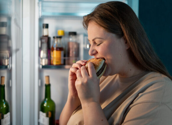 Übergewichtige Frau isst Burger
