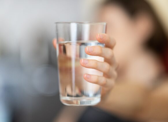 Person hält ein Glas Wasser in der Hand.