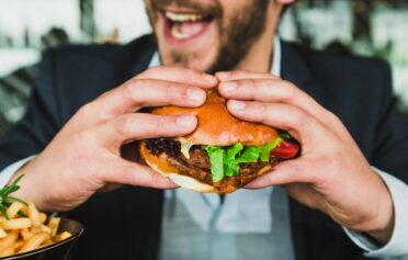 Mann, der genüsslich einen Burger isst