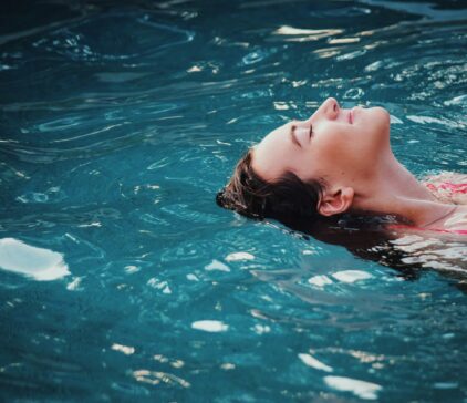 Frau liegt entspannt im Wasser.
