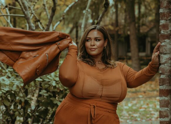 Eine selbstbewuste Plus size Frau in einem Park in orangenem Outfit
