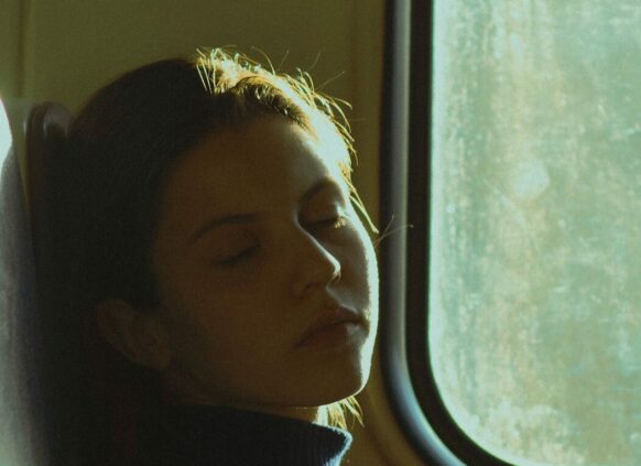 Frau schläft vor dem Fenster in der Bahn.