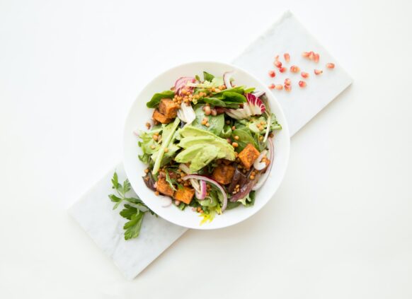 Platte auf der ein weißer Teller mit einem Salat mit Avocado und Lachs steht.