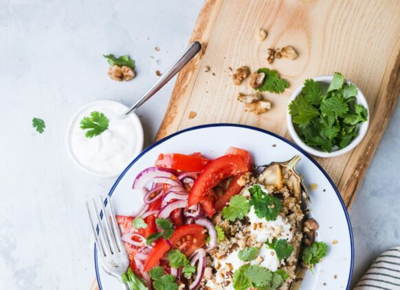 Befüllte Aubergine mit Gemüse und einem Tomatensalat als Beilage.