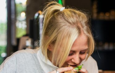 Frau isst einen Burger und vor ihr auf dem Tisch iegt noch mehr Junkfood.