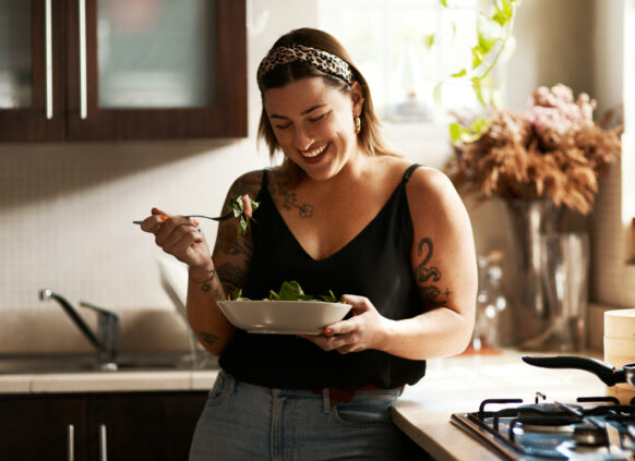 Shot of a young woman eating a healthy salad at home