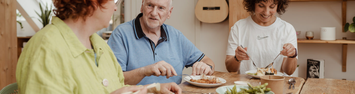 Zwei Frauen und älterer Mann essen zusammen