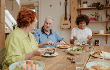 Two women and elderly men eating together