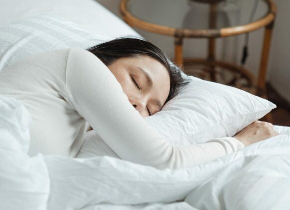 Frau schläft in einem Bett mit weißer Bettwäsche