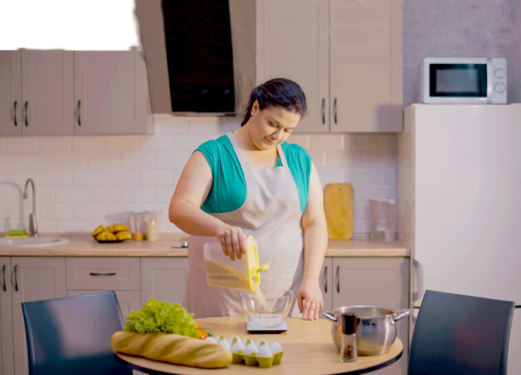 Übergewichtige Frau kocht in ihrer Küche