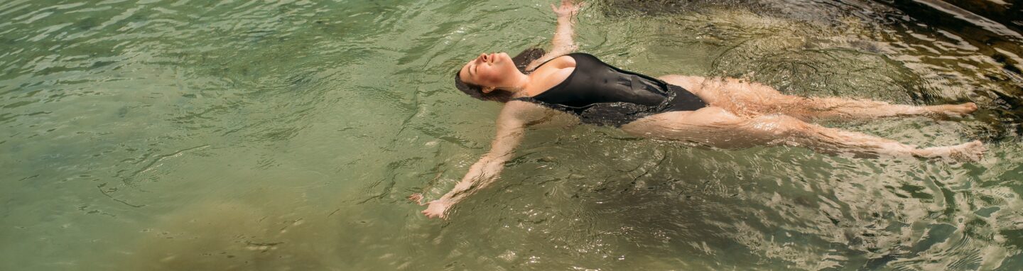 Frau liegt im Wasser und ist glücklich und zufrieden