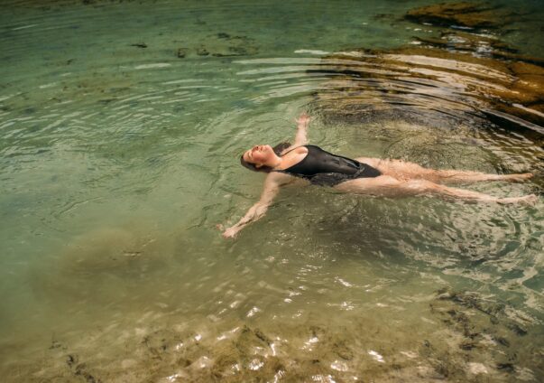 Frau liegt im Wasser und ist glücklich und zufrieden