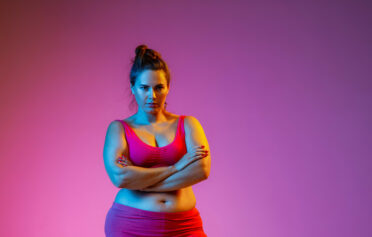 Starke Frau in Sportklamotten mit pinkem Hintergrund
