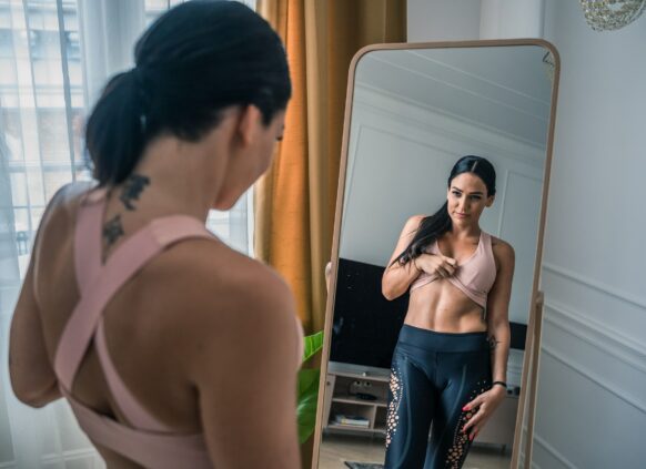 Frau schaut ihren Bauch im Spiegel an