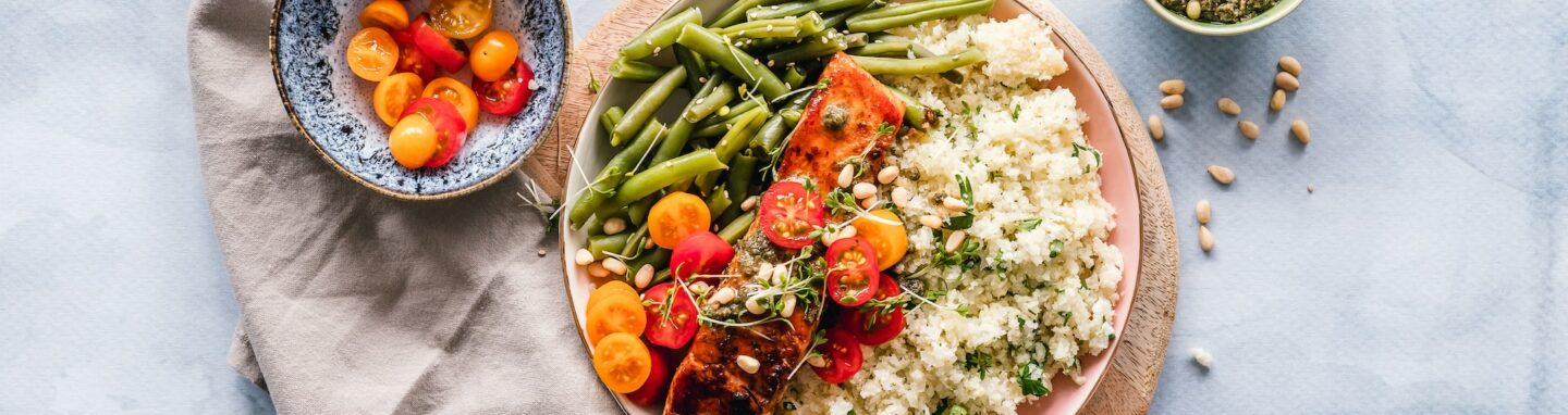 Teller mit Gemüse und Reis auf heller Tischdecke