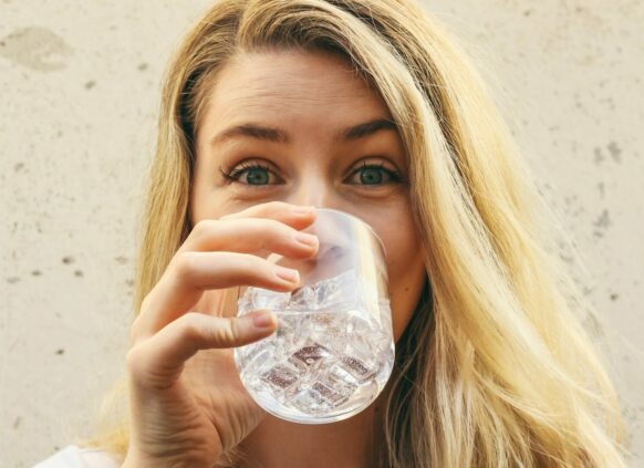 Frau mit langen blonden Haaren trinkt Wasser