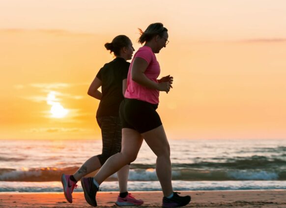 Frauen joggen am Strand bei Sonnenuntergang