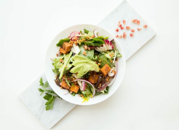 Platte auf der ein weißer Teller mit einem Salat mit Avocado und Lachs steht.