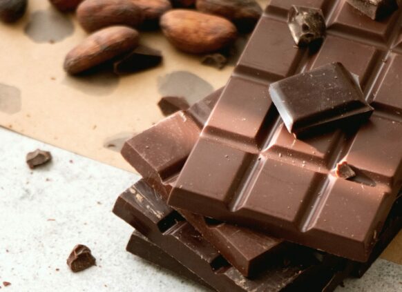 drei Tafel Schokolade gestapelt, daneben liegen Kakao Bohnen