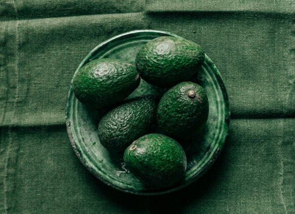 Avocados auf einem grünen Teller auf einer grpnen Decke.