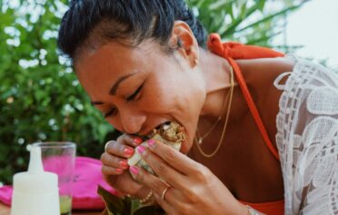 Eine asiatische Frau isst einen Burrito und sieht sehr glücklich dabei aus.