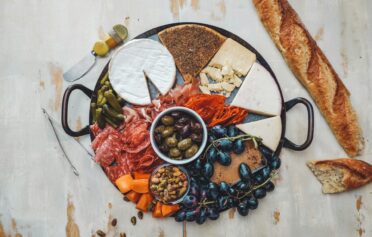 Eine Platte mit mediterraner Feinkost aus Oliven, Schinken und Käse.