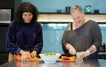 Zwei Frauen kochen gemeinsam und schneiden Gemüse.