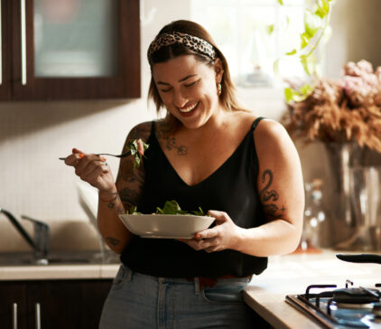 Shot of a young woman eating a healthy salad at home