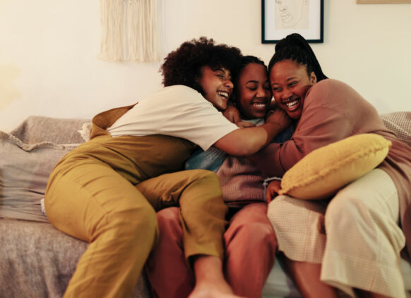 Women laughing and hugging on a sofa