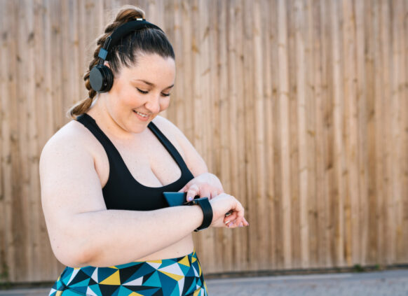 Happy woman in exercise wear checking her smartwatch