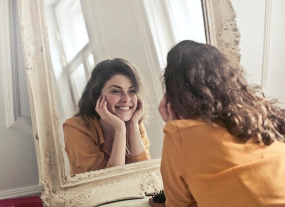 Woman happily looking at herself in the mirror